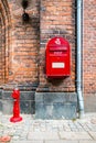 Red fire hydrant and red postal box against brick wall in Helsingor, Denmark
