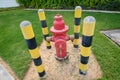 Red fire hydrant surrounded by yellow-black pillars against a green lawn. Prevention system. Royalty Free Stock Photo