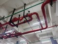 Red fire sprinkler system pipes and valves installed under ceiling structure for building safety and industrial fire suppression. Royalty Free Stock Photo