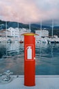 Red fire stand with a fire extinguisher inside stands on a yacht pier