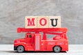 Red fire truck hold block in word MOU Abbreviation of memorandum of understanding on wood background