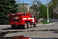 Red fire truck rides along the road from the garage to emergency call, back view with reflection in puddles