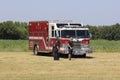 A Red Fire Truck at the Flying Farmers fly in sitting by the runway with tree`s and blue sky.