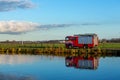 A red firetruck driving along the river the Ringvaart in Lisse