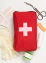 Red first aid medical kit bag with scissors, tape and gloves top view flat lay from above over white Royalty Free Stock Photo