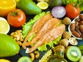 Red fish, avocado, kiwi nuts salad antioxidant dieting on a black wooden background, healthy food Royalty Free Stock Photo