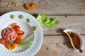 Red fish fillet with cherry tomato salad, celery and pumpkin seeds and dressing on a wooden table, top view