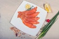 Red fish sliced in slices lies on a white plate. Around vegetables and slivers