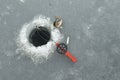 Red fishingrod next to a hole in the ice and a jumping perch Royalty Free Stock Photo