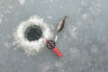 Red fishingrod and a silver lure next to a hole in the ice and a perch Royalty Free Stock Photo