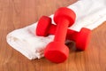 Red fitness dumbbell on white towel at wooden hame floor