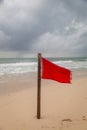 A red flag warning of rough and dangerous surf condition on a beach after a recent hurricane.