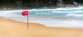 Red flag no swimming here sign at beach in windy day Royalty Free Stock Photo