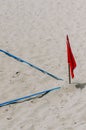 Red flag placed on a sandy beach, indicating the boundaries of a sporting field