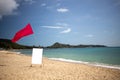 Red flag and a sign with a copy space on an empty tropical beach on a nice day. Royalty Free Stock Photo