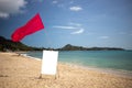 Red flag and a sign with a copy space on an empty tropical beach on a nice day. Royalty Free Stock Photo