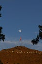 Red flag at sunset against a blue sky with large visible moon Royalty Free Stock Photo