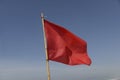 Red flag swaying in the wind on a blue sky background. Royalty Free Stock Photo