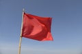 Red flag swaying in the wind on a blue sky background. Royalty Free Stock Photo