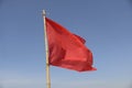 Red flag swaying in the wind on a blue sky background. Royalty Free Stock Photo