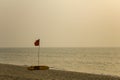 red flag swimming is prohibited and a yellow rescue surf board on a sandy beach against the sea in bad weather