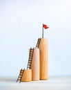 Red flag on top of wooden sticks bar graph chart steps with ladders, isolated on white background. Royalty Free Stock Photo