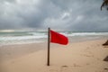 A red flag warning of rough and dangerous surf condition on a beach after a recent hurricane.