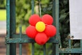 red flower made from a balloon hanging on a fence.