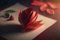 a red flower and paper, in the origami technique, lies on a white sheet of paper lying on a table Royalty Free Stock Photo