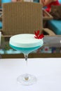 Red flowers on a Blue Daikiri cocktail in a glass goblet on a white background. Alcoholic drink. Vertical orientation