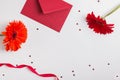 Red flowers, envelope, ribbon and star shaped confetti on white background Royalty Free Stock Photo