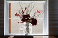 Red flowers in a vase in a white framed window in a cafe. Royalty Free Stock Photo
