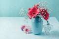 Red flowers in vase with women perfume over blue background