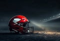 Red football helmet sits on dirt field with spotlight shining on it. Royalty Free Stock Photo