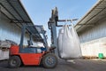 Red forklift lifts big white heavy sack