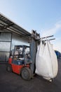 Red forklift lifts big white heavy sack