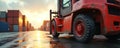 Red forklift waits in wet container yard. Stacks of cargo containers form background. Sunlight reflects on wet pavement, creating Royalty Free Stock Photo