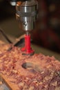 Red Forstner Bit Drills a Large Round Hole in a Wooden Breadboard