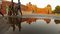 Red fort old Delhi Indian citizen walk reflections in water of puddle