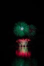 Red fountain and green starts from rich fireworks over Brno`s Dam with lake reflection Royalty Free Stock Photo