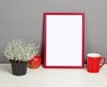 Red frame mockup with plant pot, mug and apple on wooden shelf Royalty Free Stock Photo