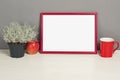 Red frame mockup with plant pot, mug and apple on wooden shelf Royalty Free Stock Photo