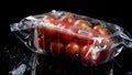 Red fresh cherry tomatoes in a plastic box wrapped in oilcloth transparently rotating on a black background