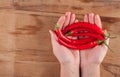 Red fresh chilli in hand on wood desk.