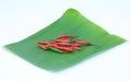 Red fresh chillies on banana leaves against white background Royalty Free Stock Photo