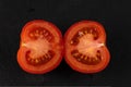 red fresh cut in half tomato on black plate Royalty Free Stock Photo