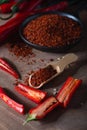 Red fresh hot chilli peppers with green tails and dried red chilli flakes in bowl on wooden board Royalty Free Stock Photo