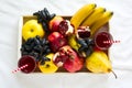 Red fresh juice with apples, pears, bananas, grapes and pomegranate fruits in white wooden tray on bed sheet Royalty Free Stock Photo