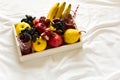 Red fresh juice with apples, pears, bananas, grapes and pomegranate fruits in white wooden tray on bed sheet. Royalty Free Stock Photo