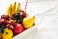 Red fresh juice with apples, pears, bananas, grapes and pomegranate fruits in white wooden tray on bed sheet. Royalty Free Stock Photo
